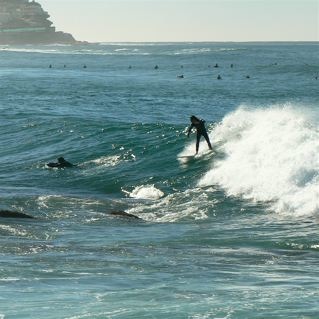 It looks like he is surfing dangerously close to the rocks - but he is running away from them to the right on the wave.